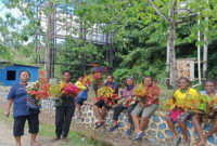 Masyarakat Papua berdiri memegang bunga menanti iring-iringan jenazah mantan Gubernur Papua Lukas Enembe di Kampung Harapan, Kabupaten Jayapura, Papua (ANTARA/Agustina Estevani Janggo)
