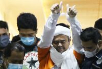 Imam Besar Front Pembela Islam (FPI) Habib Rizieq Shihab (tengah) berjalan menuju mobil tahanan usai diperiksa di Mapolda Metro Jaya, Jakarta, Minggu (13/12/2020) dini hari. Rizieq Shihab ditahan penyidik Ditreskrimum Polda Metro Jaya untuk kepentingan penyidikan perkara kasus dugaan pelanggaran protokol kesehatan COVID-19 terkait kerumunan di Petamburan, Tanah Abang, Jakarta pada 14 November lalu.  ANTARA FOTO/Reno Esnir/pras.